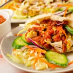 Takeaway chicken kebab recipe in a pitta bread with salad and chilli sauce on grey plate