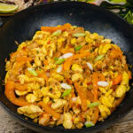 Ackee and Saltfish in a cast iron pan with chopped fresh spring onion sprinkled over the top