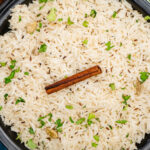 Jeera rice served in a black dish with chopped fresh coriander sprinkled over the top