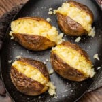 Four jacket potatoes opened up on a black plate