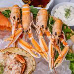 Four cooked langoustines on ice with a dressed crab and smoked salmon on the side