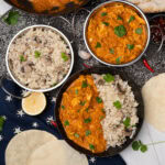 Leftover Turkey Curry and mushroom rice served in Balti dishes and a black bowl with coriander over the top with poppadoms round the bowl