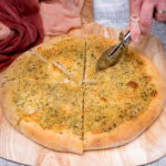 Cutting the Garlic Pizza Bread with a pizza slicer