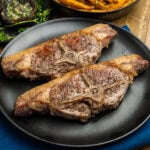 Two cooked Barnsley chops served on a black plate