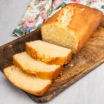 Madeira Cake on a wooden chopping board with three slices of it been cut
