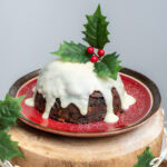 Slow Cooker Christmas Pudding coated in brandy sauce and a holly decoration on top