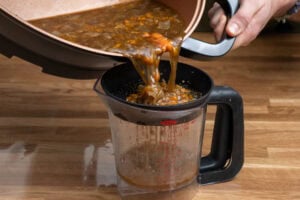 Pouring the mashed veg and stock into a sieved jug