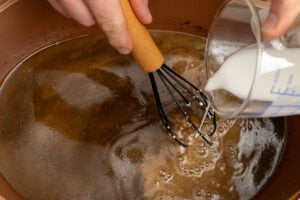 Pouring cornflour slurry into the gravy to thicken and whisking