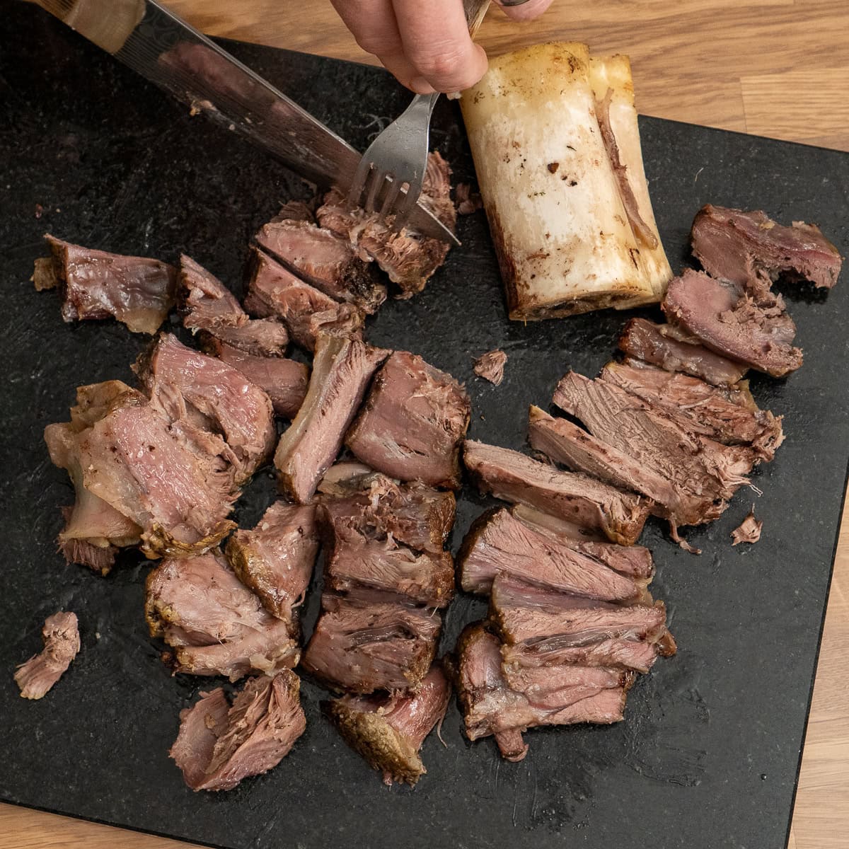 Slicing the beef shin on a black chopping board