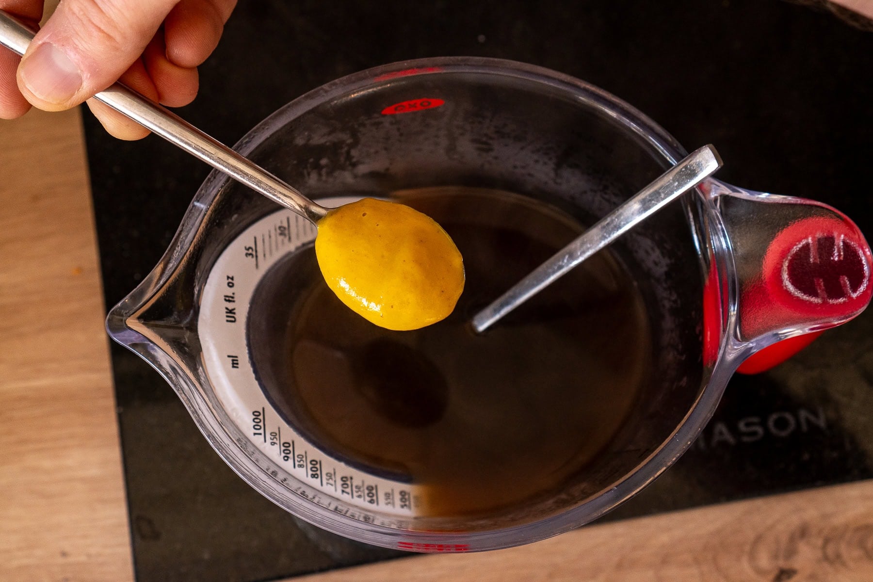 Putting a teaspoon of English mustard into a jug beef stock
