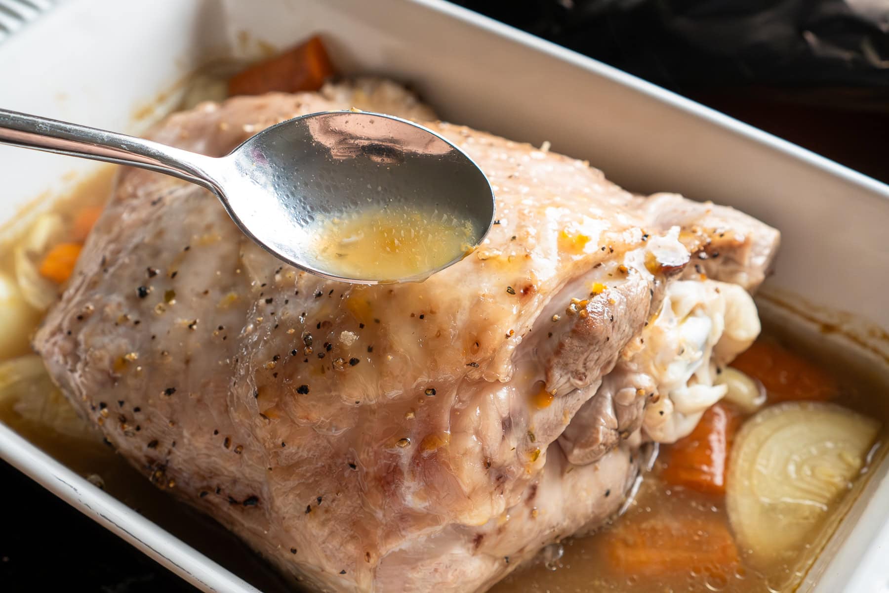 Basting the turkey thigh with the stock using a spoon