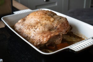 Cooked turkey thigh in a dish sitting on a veg trivet