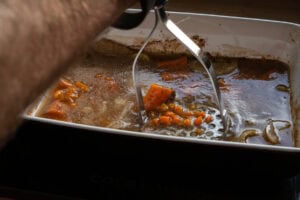 Mashing the chopped onions and carrots in the stock with a masher