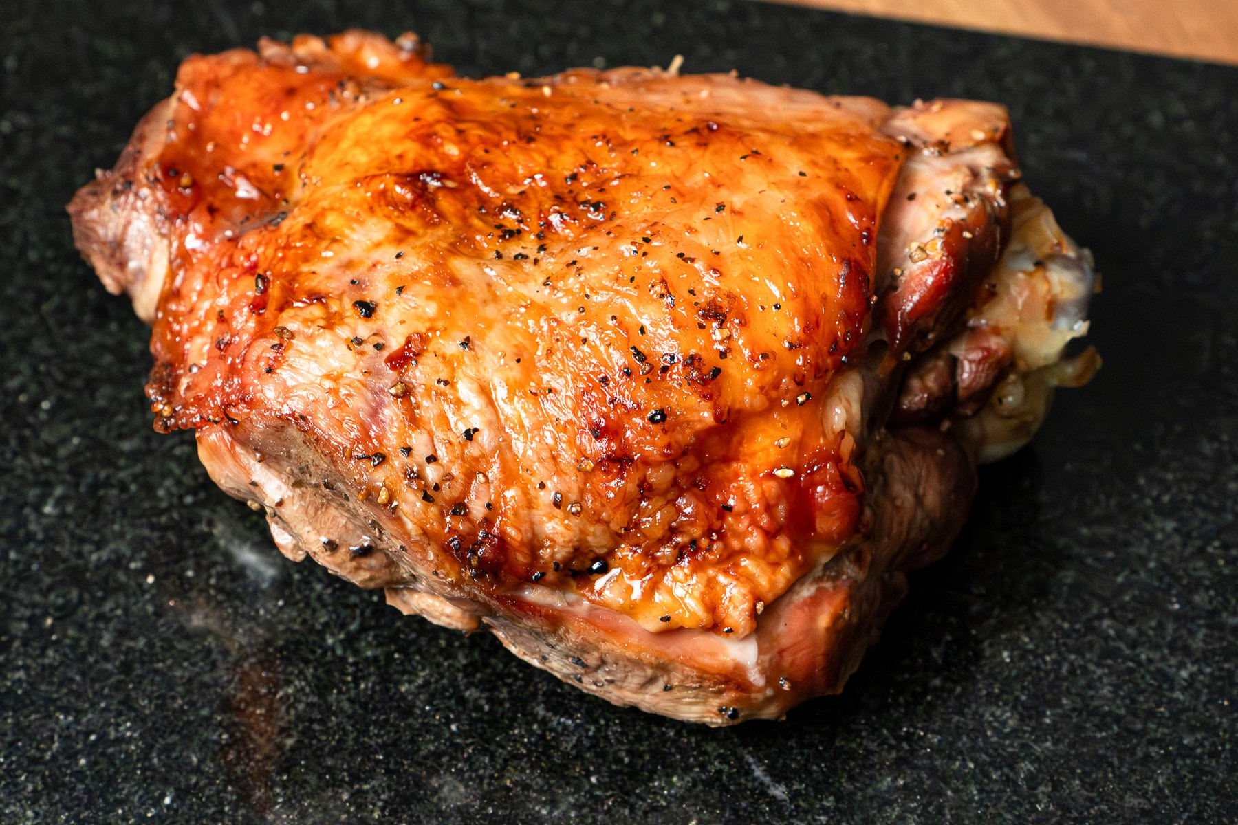 A turkey thigh on a black chopping board