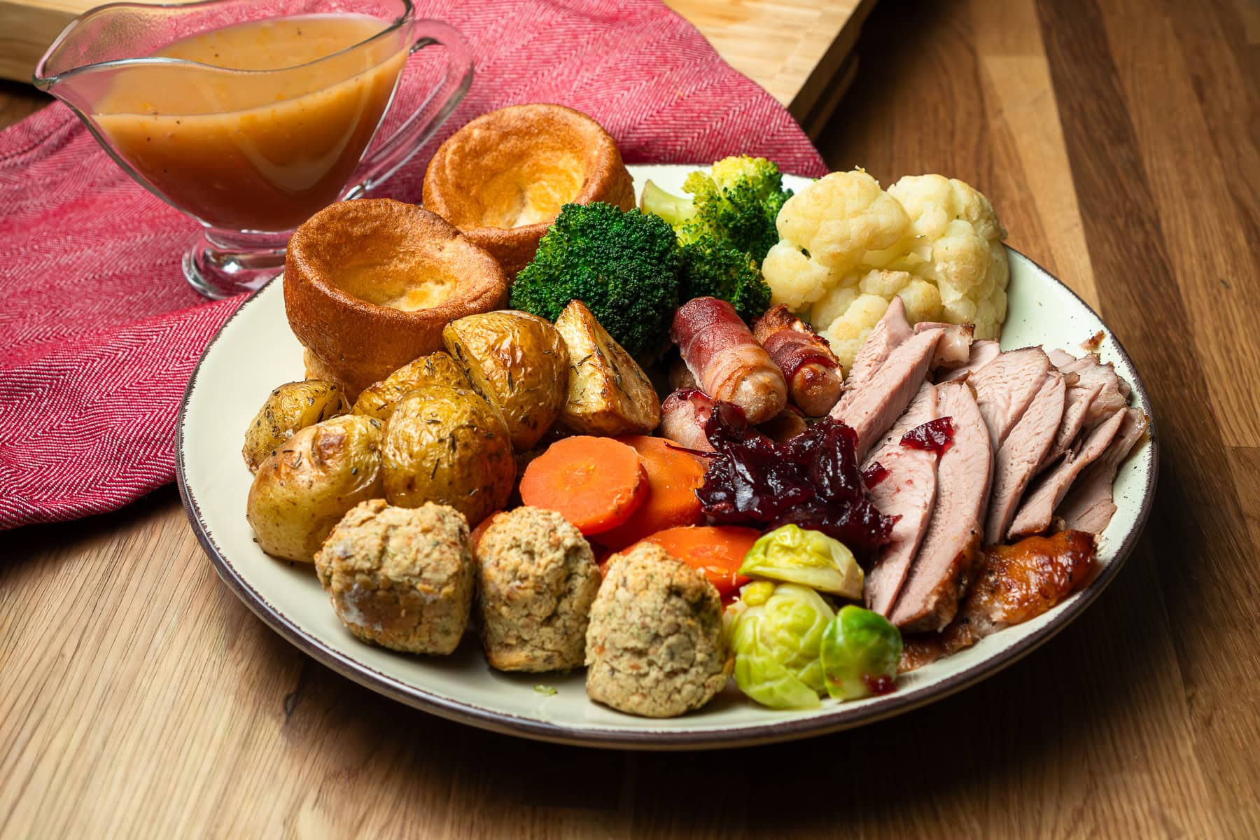 Sliced turkey thigh Christmas roast dinner consists of turkey thigh, cauliflower, broccoli, Brussels stuffing balls, Yorkshire puddings and roast potatoes