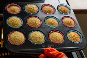 Twelve fairy cakes cooked in a tray coming out the oven