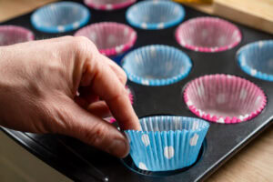 Placing cup cake cases into a oven tray by hand