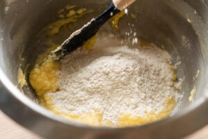 Adding flour to the fairy cake mixture in a large mixing bowl