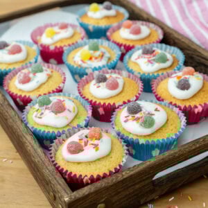 Fairy cakes in a tray decorated in icing sprinkles and sweets