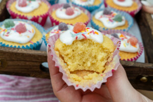 A fairy cake that has had a bite out of it showing the fluffy texture of the cake