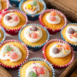 A tray of fairy cakes decorated in icing, sprinkles and sweets