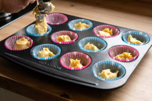 Putting the cake mixture into cases using a spoon