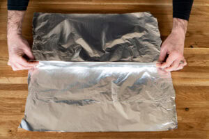 Folding two sheets of aluminium sheets of foil together by making a fold in the middle connecting the sheets together