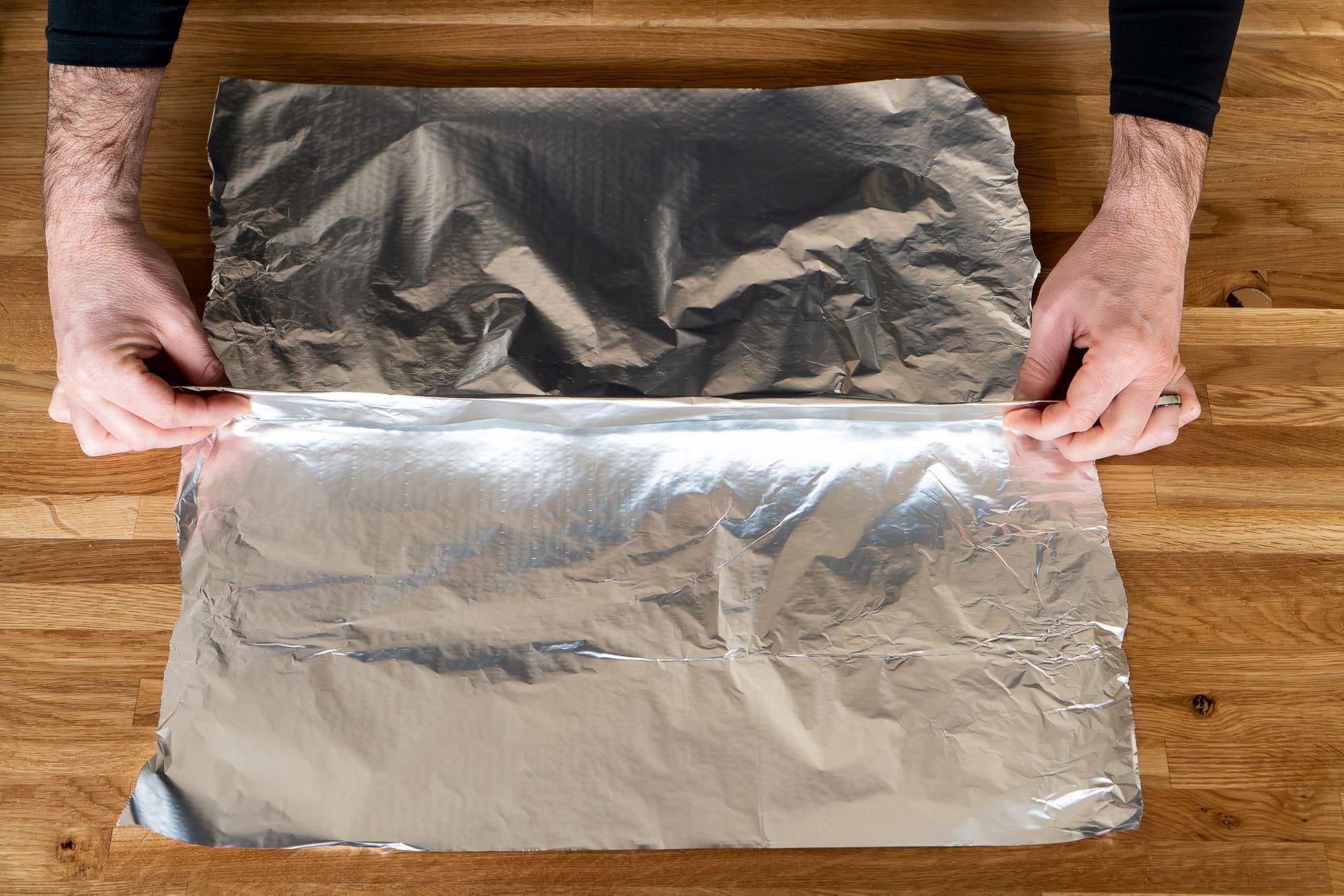 Folding two sheets of aluminium sheets of foil together by making a fold in the middle connecting the sheets together