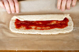 Rolling the suet dough coated with jam using the parchment paper