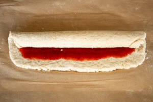 Rolling the suet dough coated with jam forming the jam roly poly