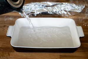 Pouring boiling water from a kettle into an oven proof dish