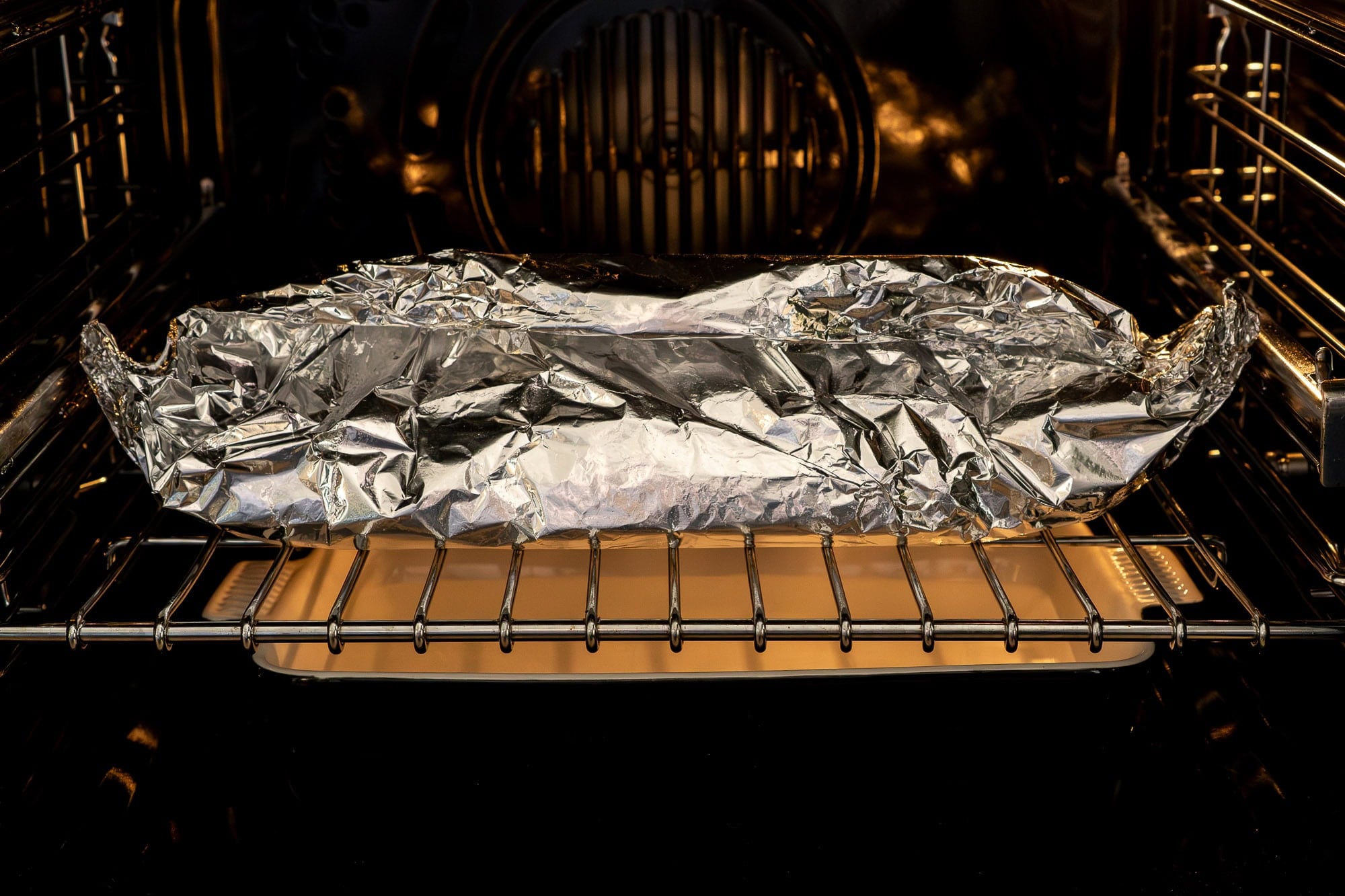 Jam roly poly wrapped in parchment paper and foil in the oven
