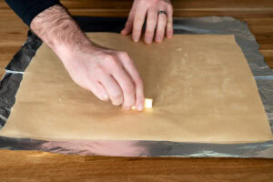 A sheet of parchment paper on top of the foil sheets being coated in butter