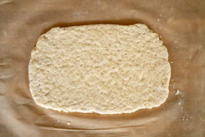 suet dough rolled out flat on a sheet of parchment paper
