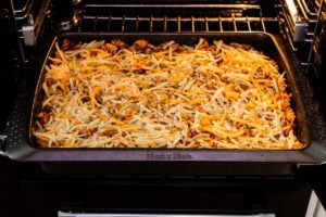 Sausage Pasta Bake with grated cheese on top going in the oven to cook