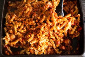 Mixing the cooked pasta with sausage tomato sauce together