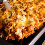 Sausage tray bake Pasta being picked up with a large spatula