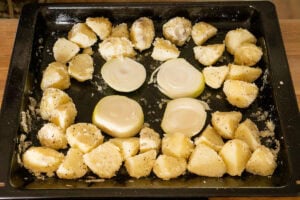 Potatoes and onions on baking tray ready for beef