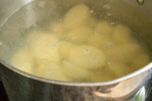 Potatoes parboiling in a saucepan before roasting.