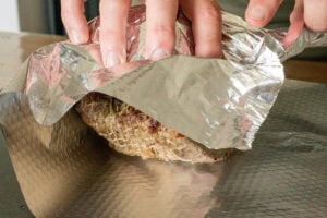 Roast top rump beef resting loosely wrapped in foil after cooking.