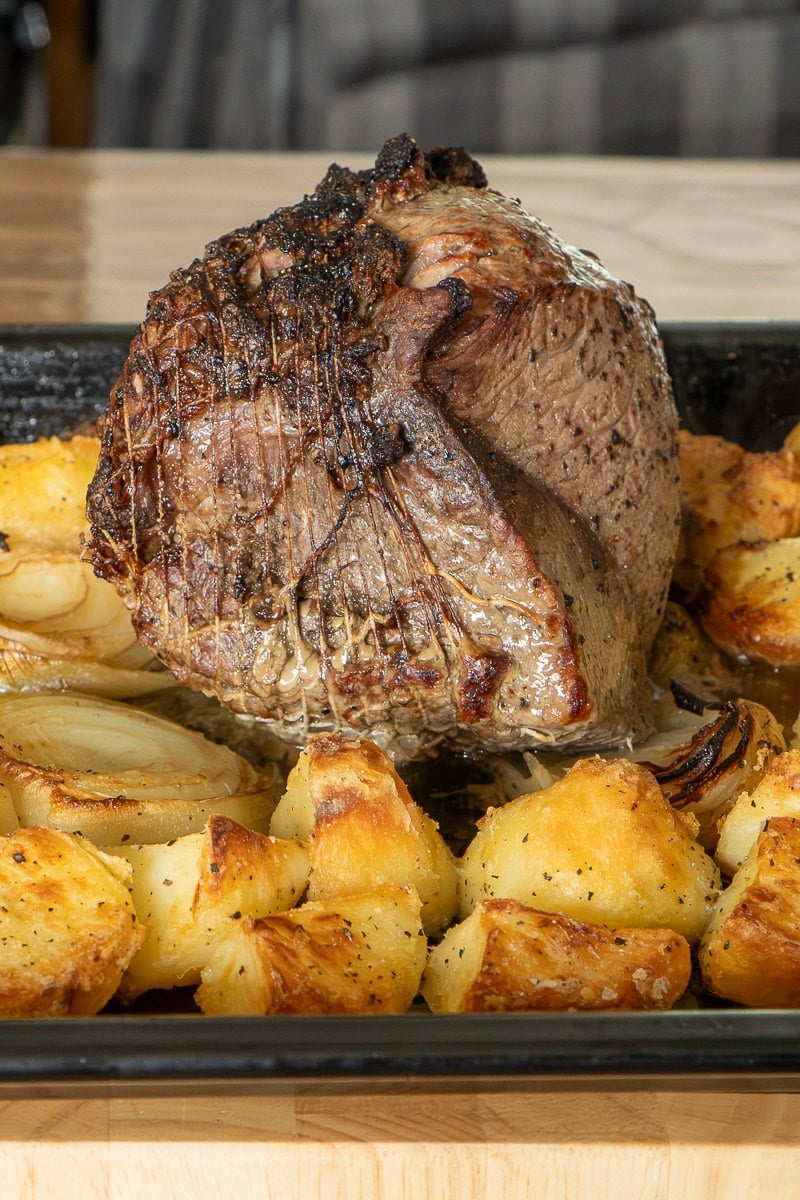 Roast top rump beef cooked to medium with roast potatoes before the beef is removed to rest.