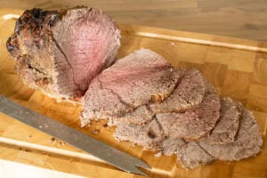 Sliced joint of roast beef on chopping board