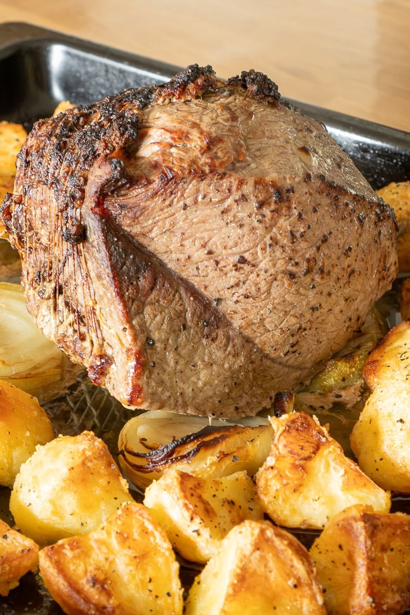 Top rump beef roasted sitting on onion quarters with crispy roast potatoes