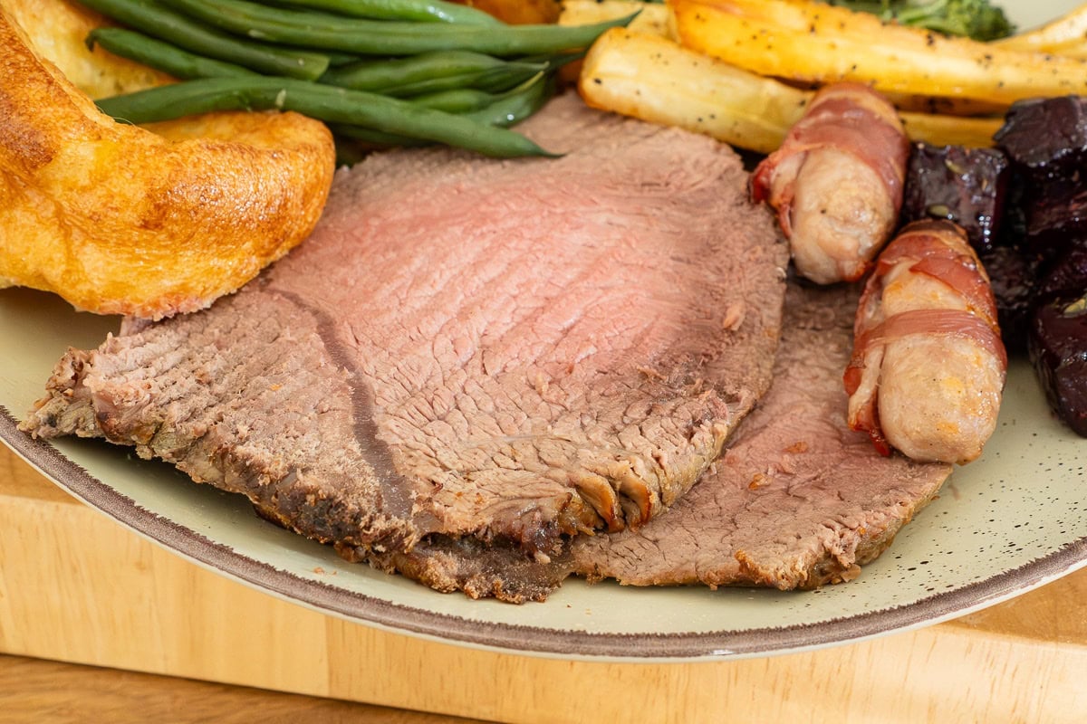 2 slices of roast beef with pigs in blankets, yorkshire pudding, green beans and roast parsnips