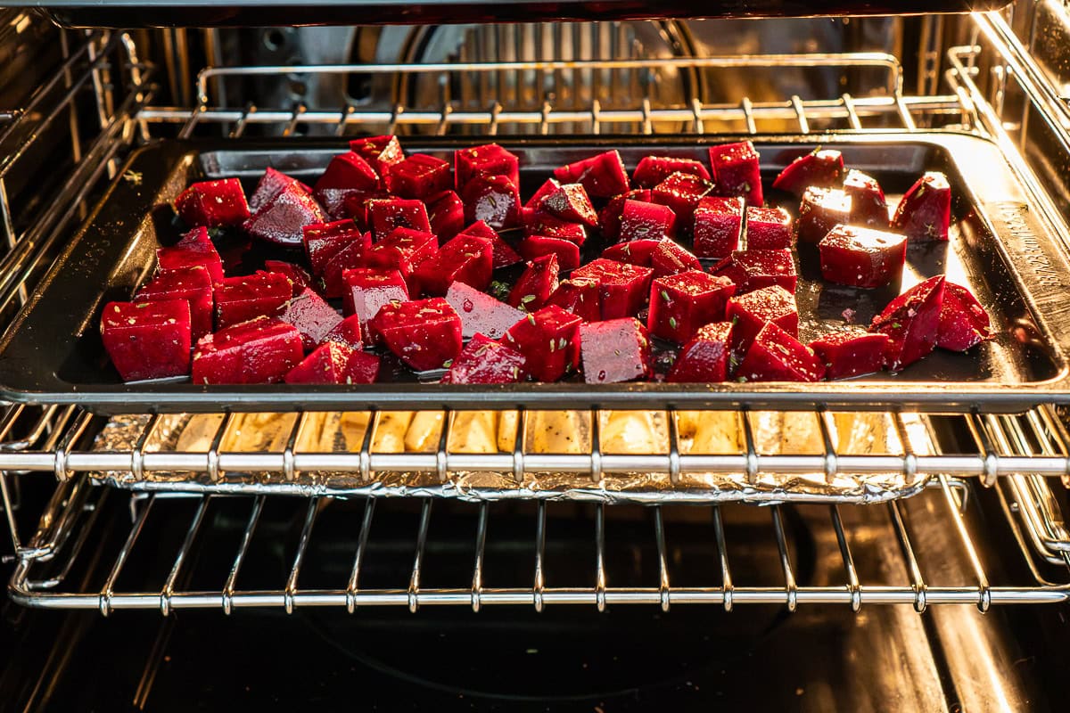 Roasted beet cubes on a baking tray in an oven.