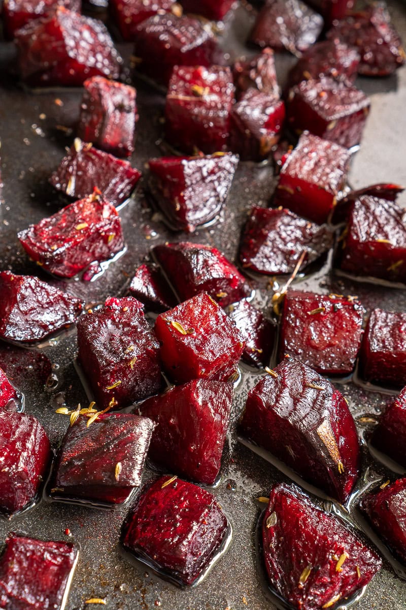 Beetroot cubes seasoned with herbs on a dark surface.