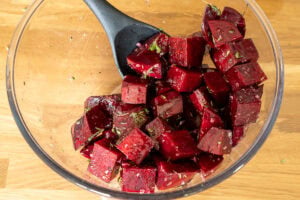 Beetroot cubes in bowl with herb seasoning.