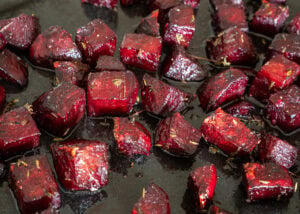 Beetroot cubes being fried or roasted on a dark surface.