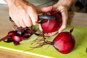 Person slicing red beet on a lime cutting board for flawless food photography.