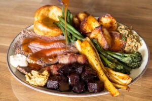 Succulent roasted beef with carrots, greens, potatoes and beetroot on a plated meal.